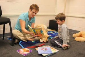 Young child receives animal-assisted therapy from counselor and dog