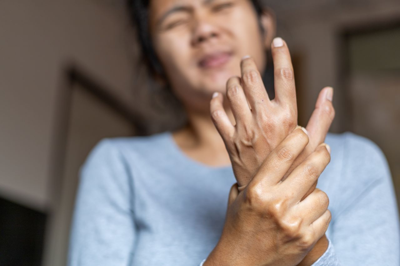 A young woman with wrist pain is holding her wrist and has a painful expression on her face 