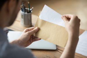 close up of man holding envelope with a letter inside