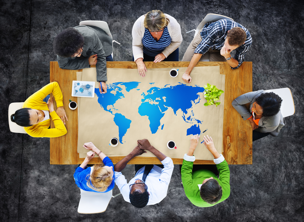 A group of adults sitting around a table with a world map in front of them