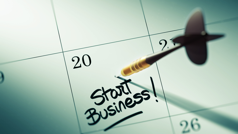 A calendar with a note that reads "start business" and has a dart above the words