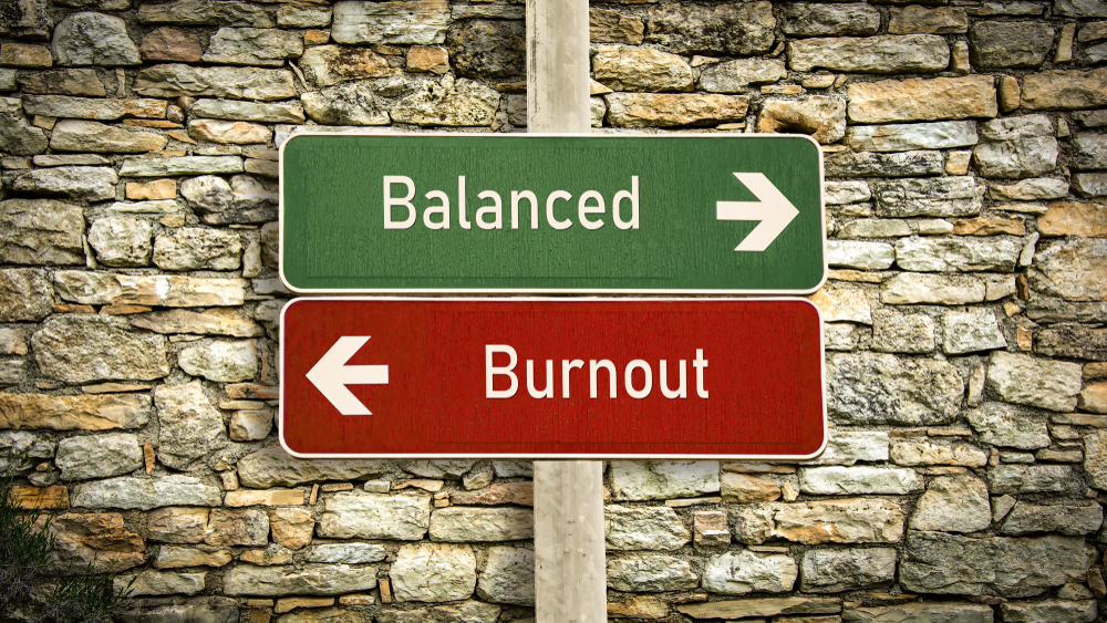 A green sign saying "balanced" with an arrow pointing to the right and a red sign saying "burnout" with an arrow pointing to the left
