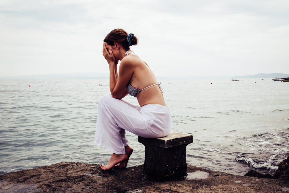 A worried, sad, depressed person sitting beside the seaside